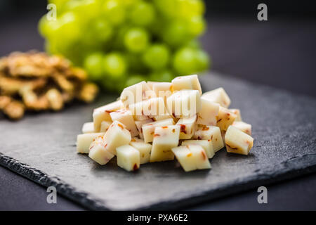 Pezzi di formaggio di uva succosa e noci sulla scheda di ardesia. Foto Stock