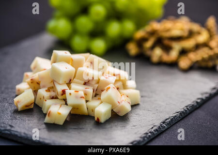 Pezzi di formaggio di uva succosa e noci sulla scheda di ardesia. Foto Stock