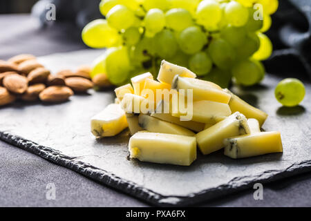 Pezzi di formaggio di uva succosa e noci sulla scheda di ardesia. Foto Stock