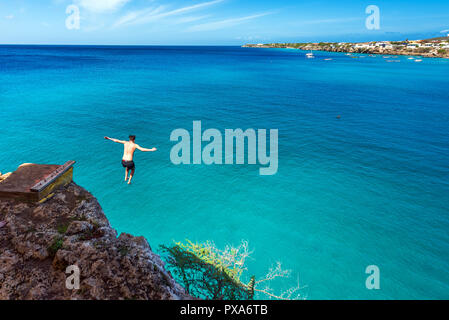 WESTPUNT, CURASAO - 23 gennaio 2018: uomo salta fuori da una scogliera. Copia spazio per il testo. Vista posteriore Foto Stock