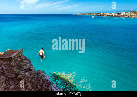 Uomo salta fuori da una scogliera, Westpunt, Curacao, Paesi Bassi. Copia spazio per il testo Foto Stock