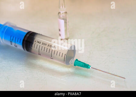 Una siringa e un flaconcino di farmaco sul tavolo vicino Foto Stock