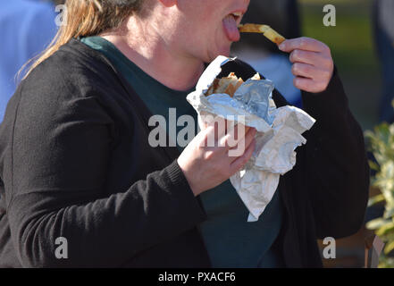 Signora obesi mangiare fast food in strada nel Regno Unito dove alto strade hanno la più alta concentrazione di fast food in quasi un decennio Foto Stock