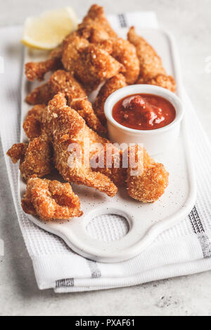 Pollo fritto con salsa di pomodoro su una lavagna bianca. Foto Stock