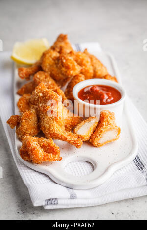 Pollo fritto con salsa di pomodoro su una lavagna bianca. Foto Stock