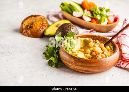 Avocado hummus in una ciotola di legno con verdure. Sano cibo vegan concetto. Foto Stock