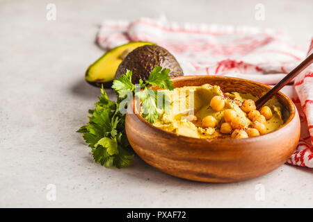 Avocado hummus in una ciotola di legno con verdure. Sano cibo vegan concetto. Foto Stock