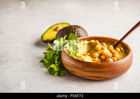 Avocado hummus in una ciotola di legno con verdure. Sano cibo vegan concetto. Foto Stock