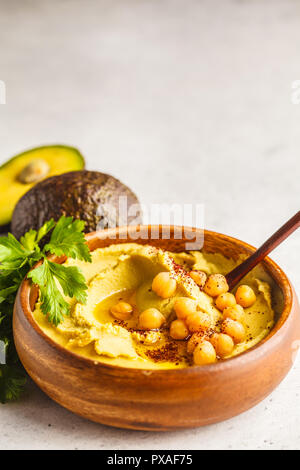 Avocado hummus in una ciotola di legno con verdure. Sano cibo vegan concetto. Foto Stock