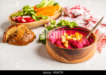 Hummus di barbabietole in una ciotola di legno con verdure. Impianto basato dieta concetto. Foto Stock