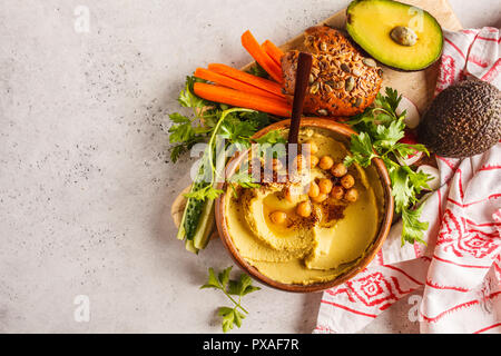 Avocado hummus in una ciotola di legno con verdure. Foto Stock