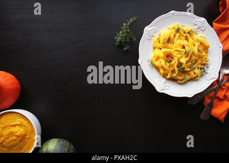 Tagliatelle con crema di zucca salsa sopra lo sfondo nero.vista superiore Foto Stock