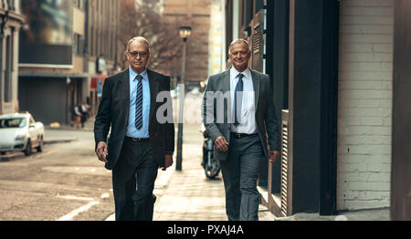 Due senior business persone camminare al fianco di un edificio per uffici. Business di successo partner camminare insieme all'esterno. Foto Stock