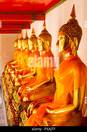 Fila di seduta statue di Buddha all'interno di Wat Pho o il Tempio del Buddha reclinato, Bangkok, Thailandia Foto Stock