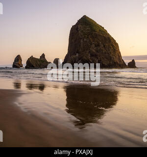 La Haystack Rock al tramonto, iconico mare di uno stack o di uno sperone roccioso della costa del Pacifico, Cannon Beach, Oregon, Stati Uniti d'America. Foto Stock