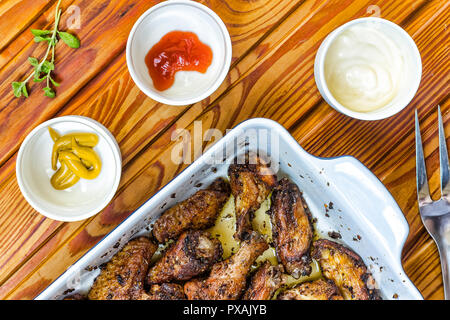 Mangiare fuori. Ali di pollo con una varietà di salse barbecue Foto Stock