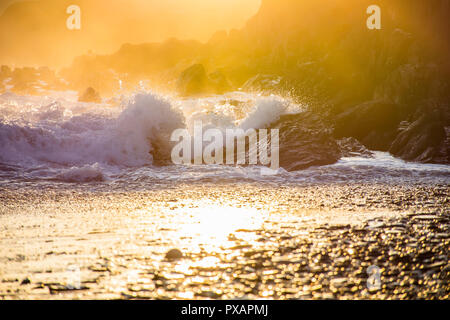 Tramonto spettacolare scena sul roccioso e misty spiaggia vicino Tenby Il Pembrokeshire Coast,South Wales,Uk.ora d'oro paesaggio.spruzzi delle onde sugli scogli. Foto Stock