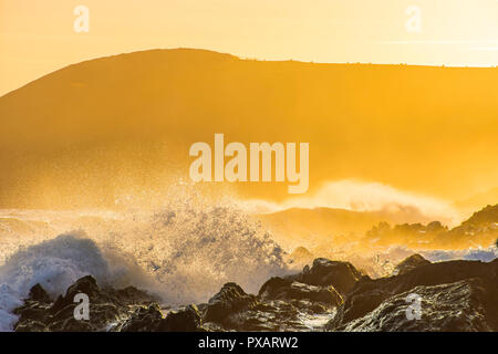 Golden Sunset over Pembrokeshire Coast nel Galles del Sud, Regno Unito.gli spruzzi delle onde e la brezza della sera, scogliere e la nebbia in background.paesaggio panoramico Uk.Magic Foto Stock