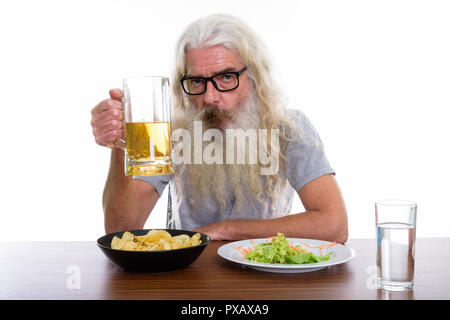 Studio shot di senior uomo barbuto tenendo un bicchiere di birra con hea Foto Stock