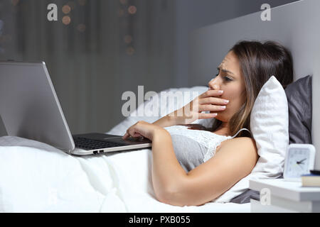 Preoccupato di trovare una donna cattiva notizia in un computer portatile sul letto nella notte a casa Foto Stock