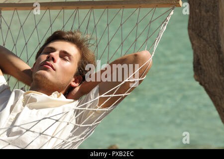 Uomo di riposo rilassante su una amaca in vacanza con un mare turchese in background Foto Stock