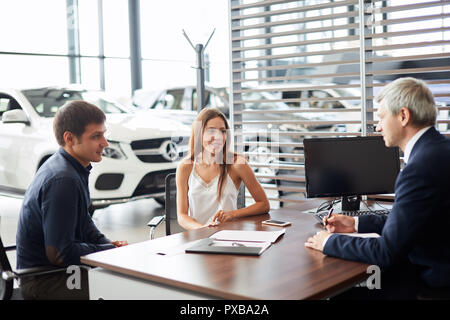 Coppia sales manager firma un contratto con i clienti alla concessionaria auto office Foto Stock