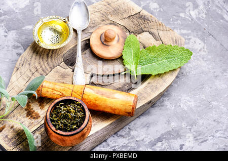 Delizioso infuso di tè alle erbe con salvia su sfondo rétro Foto Stock