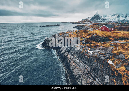 Clif con tradizionale rosso rorbu casa sulle Isole Lofoten in Norvegia Foto Stock