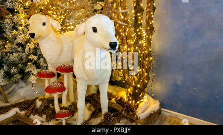 Due renne bianche e funghi vicino alle luci di natale Foto Stock