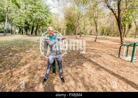 Donna anziana in abbigliamento sportivo che esercitano a Outdoor Fitness Park, uno stile di vita sano persone mature. Foto Stock