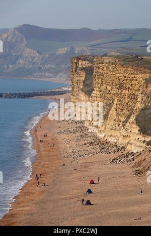 Dorset, Regno Unito. 21 ott 2018. Le persone godono di un clima caldo e ad est di scogliere visto da Burton Bradstock guardando verso il West Bay nel Dorset Credito: Finnbarr Webster/Alamy Live News Foto Stock