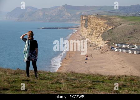 Dorset, Regno Unito. 21 ott 2018. Le persone godono di un clima caldo e ad est di scogliere visto da Burton Bradstock guardando verso il West Bay nel Dorset Credito: Finnbarr Webster/Alamy Live News Foto Stock