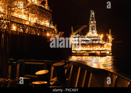 FPSO nave cisterna vicino a piattaforma petrolifera Rig di notte. Offshore industria petrolifera e del gas Foto Stock