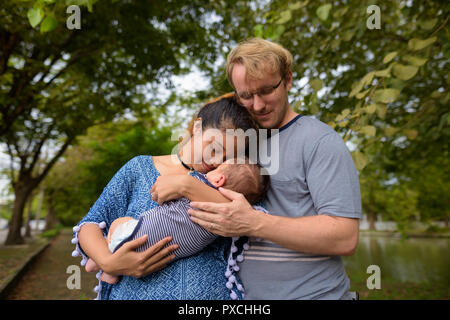 Multi-etnico giovane famiglia bonding insieme al parco Foto Stock