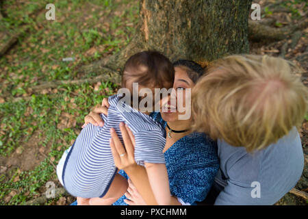 Multi-etnico giovane famiglia bonding insieme al parco Foto Stock