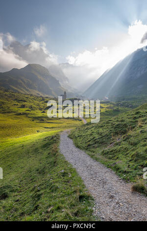 Raggi di sole illumina un piccolo villaggio nelle montagne svizzere. Uno stretto sentiero conduce al villaggio di Meglisalp. Foto Stock