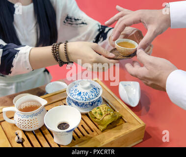 Cerimonia del tè cinese. La ragazza versa il tè dal bollitore nella coppa. L'uomo prende una tazza di le mani delle donne. Foto Stock