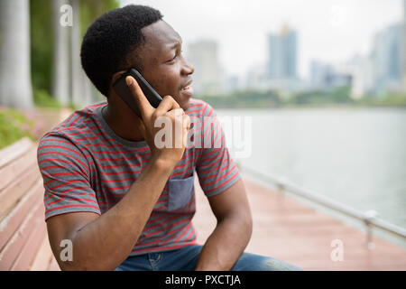 I giovani africani bello uomo che parla al telefono in posizione di parcheggio Foto Stock