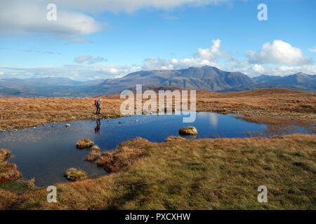 Uomo che cammina su Braigh Bhlaich alla montagna scozzese Corbett Stob coire un' Chearcaill con il Ben Nevis in background nelle Highlands Scozzesi. Foto Stock