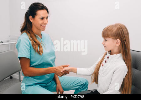 Gentile Dottore scuotendo leggermente la mano della bambina in office Foto Stock