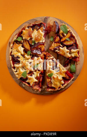 Le prugne tagliate a fette di torta su legno tagliere Foto Stock