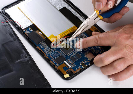 Uomo che fissa un dispositivo elettronico utilizzando pinze a becchi lunghi Foto Stock