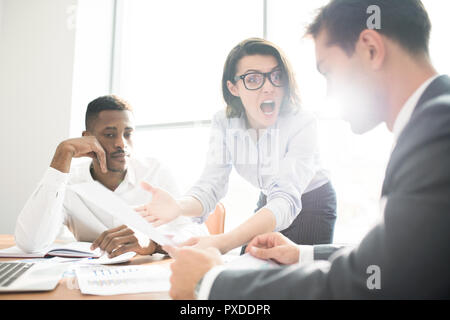 Furious lady boss gridava a subordinare alla riunione Foto Stock