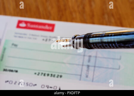 Santander check book e penna stilografica. Retrò o old school banking. La scrittura di un controllo. Foto Stock