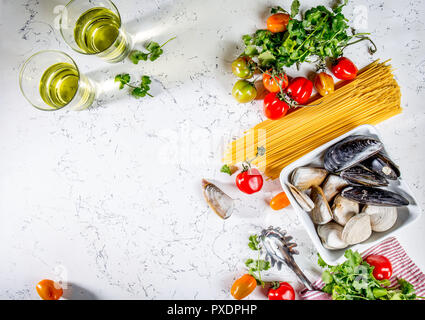 Gli ingredienti per cucinare gli spaghetti con frutti di mare. Gusci musselsa, vongole, vongole, pomodori e vino bianco. Foto Stock