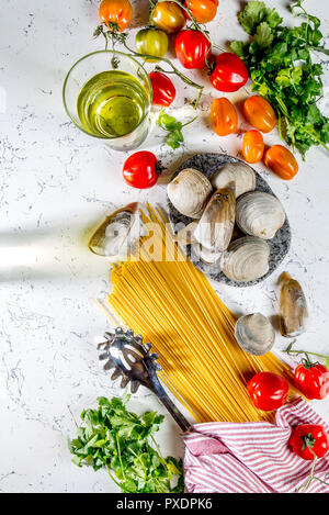 Gli ingredienti per cucinare gli spaghetti con frutti di mare. Gusci musselsa, vongole, vongole, pomodori e vino bianco. Foto Stock