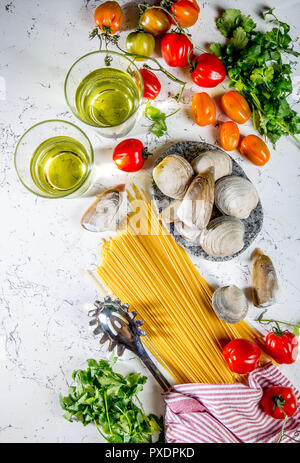 Gli ingredienti per cucinare gli spaghetti con frutti di mare. Gusci musselsa, vongole, vongole, pomodori e vino bianco. Foto Stock