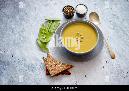 Pisello verde minestra di crema nella ciotola grigio Foto Stock