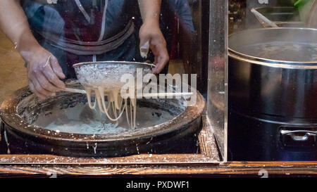 Rendendo tagliatelle cinesi nel mercato asiatico Foto Stock