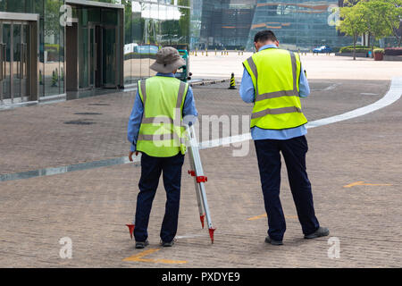 Geometra builder gli ingegneri che lavorano con apparecchiature di indagine teodolite su un cavalletto di apparecchiature di transito al sito in costruzione Foto Stock